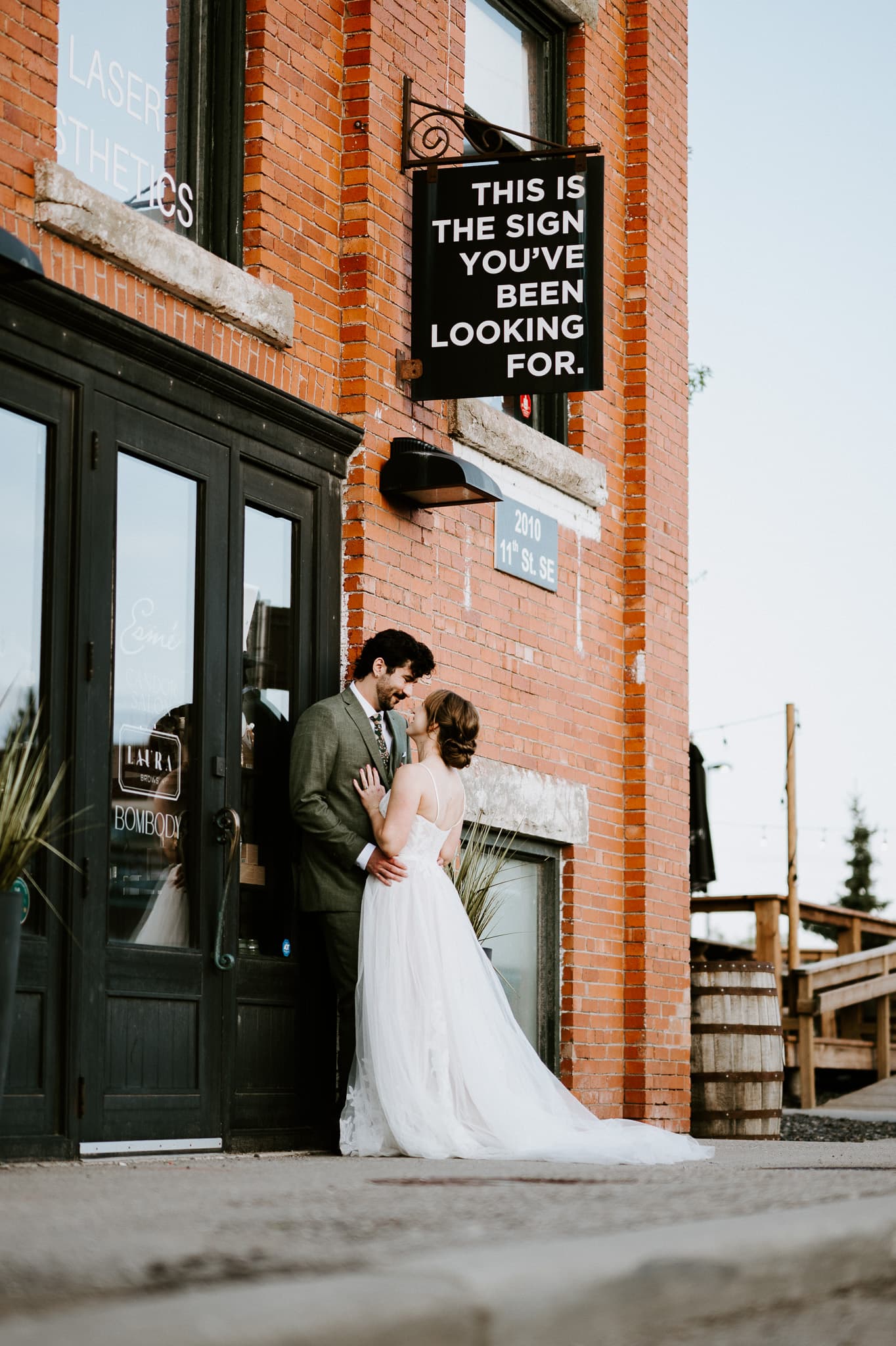 A bride and groom together outside a brick storefront at golden hour